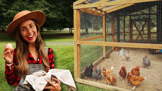 Smiling female homesteader holding a fresh egg in front of a backyard chicken coop with free-range hens.
