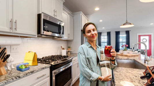 Smiling woman holding vacuum-sealed food jar in a modern kitchen using Avid Armor system