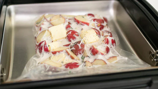 Vacuum-sealed red potatoes with garlic, herbs, and cream inside an Avid Armor chamber vacuum sealer for sous vide cooking