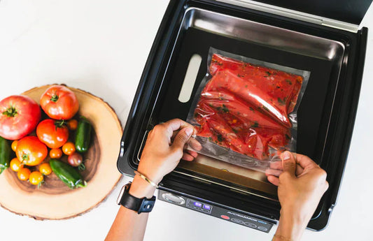 Vacuum sealing tomato-based food in chamber vacuum sealer with fresh vegetables nearby