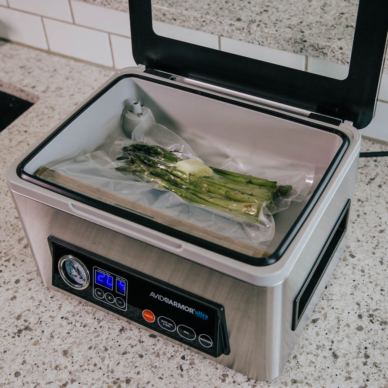 A perfectly vacuum sealed pack of Asparagus with a tab of butter sitting in the chamber of a model USV20 chamber vacuum sealer.